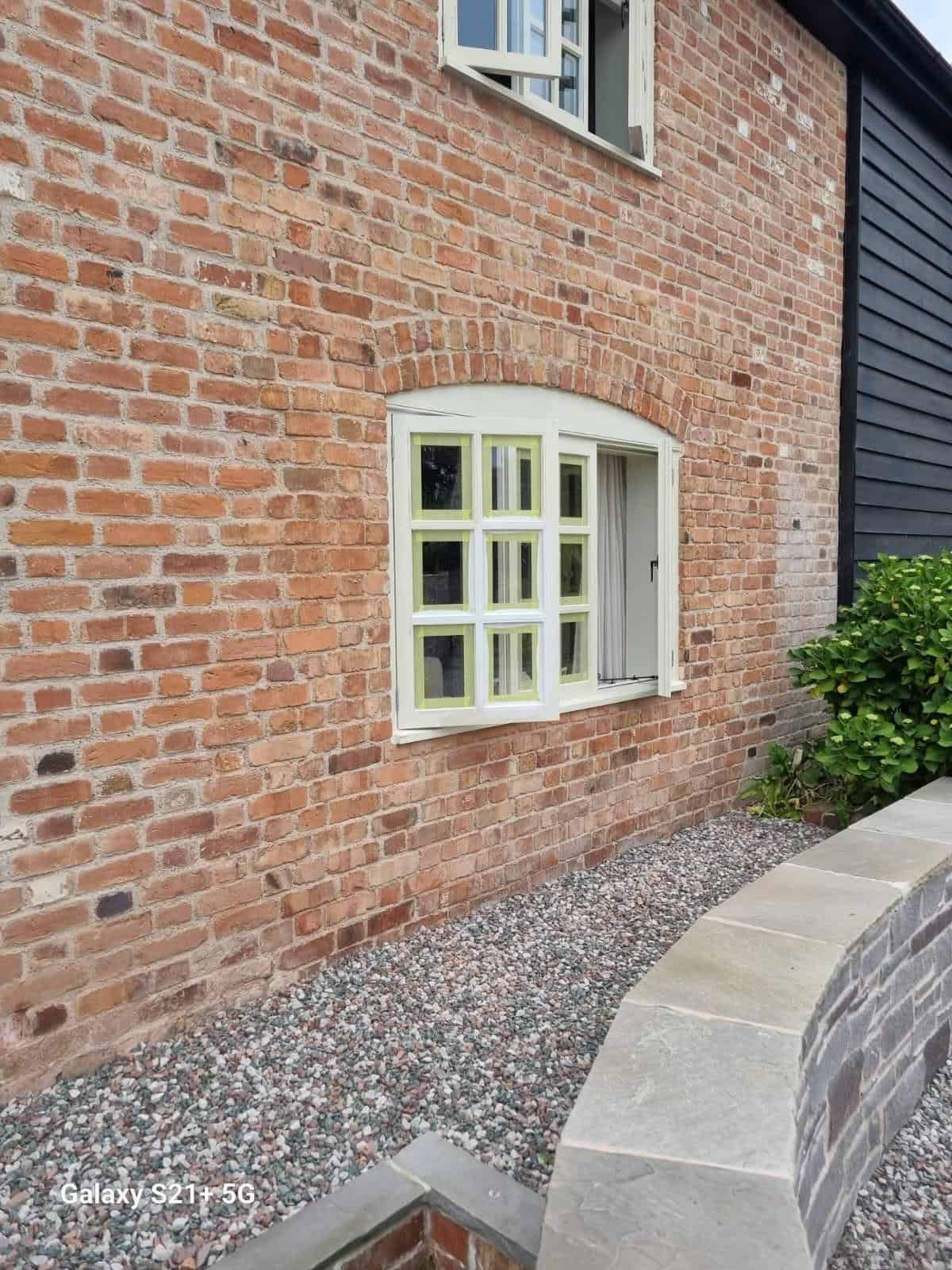 Repainted pale green timber windows on a brick farmhouse