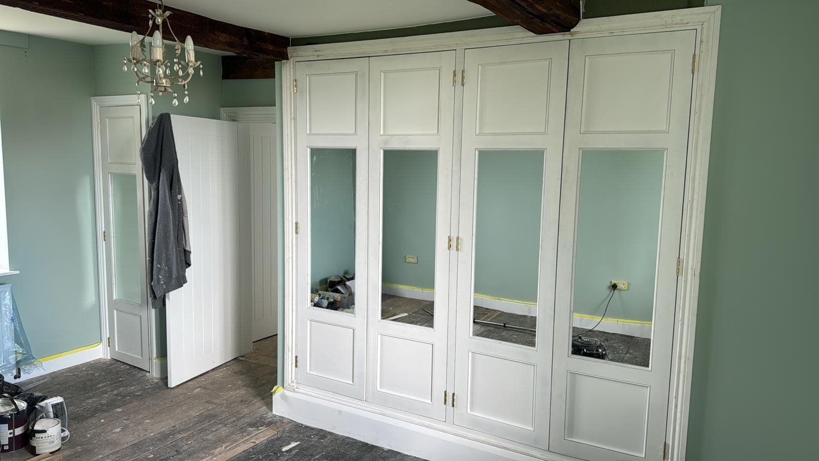 Fitted wardrobes with mirrored doors in a sage green bedroom