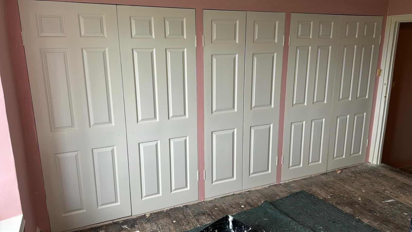 Long run of panelled white fitted wardrobes