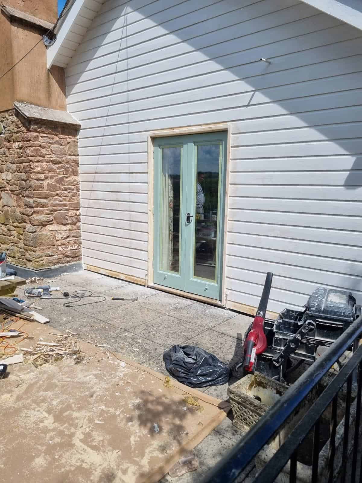 White weatherboard garden building with French doors